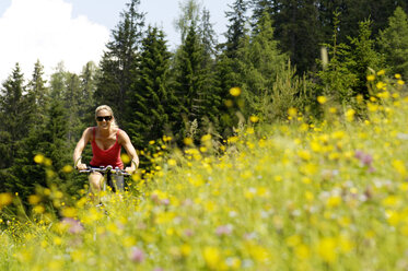 Junge Frau beim Mountainbiken im Feld - HHF00773