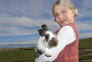 Mädchen (7-9) hält Kaninchen im Arm, Porträt, Nahaufnahme - WESTF02958