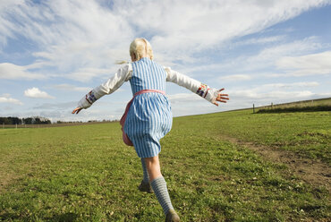 Girl (7-9) jumping in field, rear view - WESTF02955