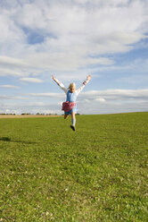 Girl (7-9) jumping in field, arms out - WESTF02953