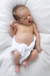 Baby in diaper lying on bed, elevated view - SMOF00092