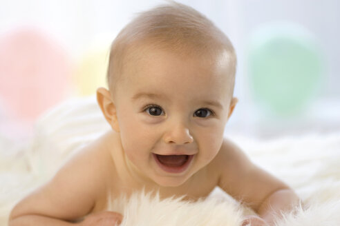 Baby boy ( 6-12 months) lying on belly, smiling - SMOF00007