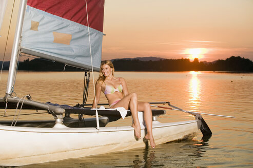Frau sitzt auf einem Segelboot bei Sonnenuntergang - ABF00114