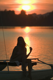 Frau sitzt auf einem Segelboot bei Sonnenuntergang - ABF00113