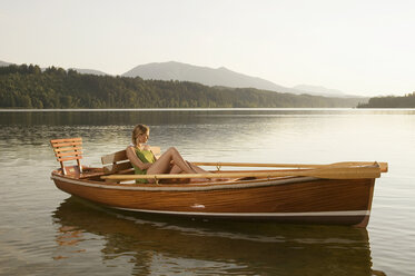 Junge Frau sitzt auf einem Ruderboot auf einem See - ABF00107