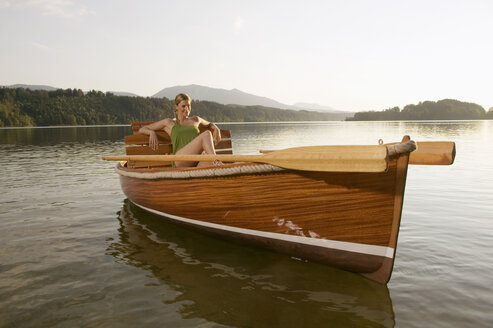 Junge Frau sitzt auf einem Ruderboot auf einem See - ABF00106