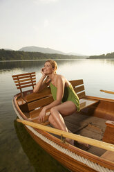 Junge Frau sitzt auf einem Ruderboot auf einem See - ABF00105