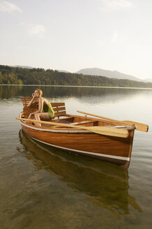 Junge Frau sitzt auf einem Ruderboot auf einem See - ABF00104
