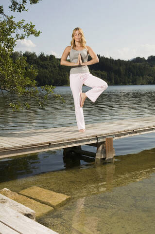 Frau übt Yoga auf dem Steg, lizenzfreies Stockfoto