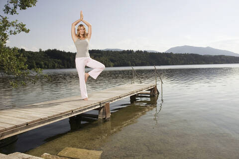 Frau übt Yoga auf dem Steg, lizenzfreies Stockfoto
