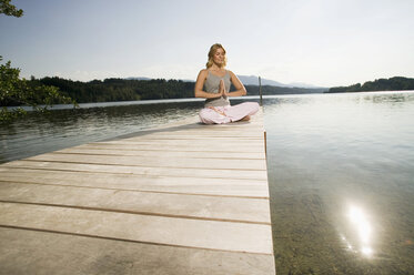 Woman exercising yoga on jetty - ABF00077