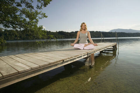 Frau übt Yoga auf dem Steg, lizenzfreies Stockfoto