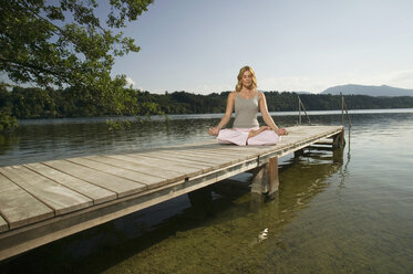 Woman exercising yoga on jetty - ABF00076