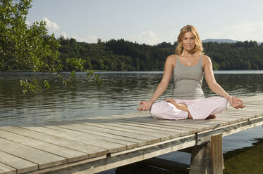 Woman exercising yoga on jetty - ABF00073