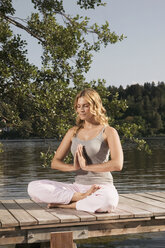 Woman exercising yoga on jetty - ABF00072