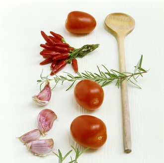 Tomatoes, chillies, garlic, rosemary and wooden spoon on kitchen table - COF00040