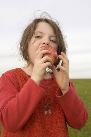 Mädchen (7-9) isst Apfel, Nahaufnahme, lizenzfreies Stockfoto