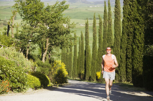 Italien, Toskana, Mann joggt auf der Straße - MRF00773