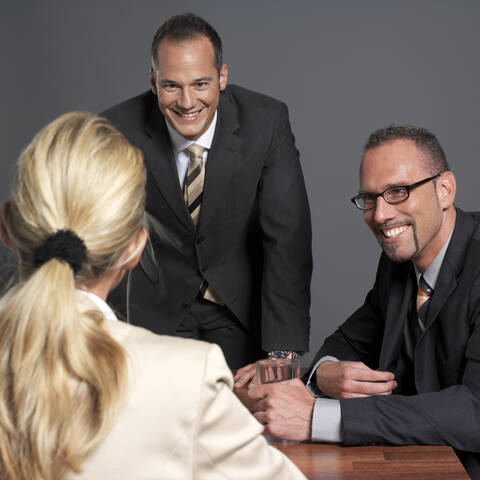 Geschäftsleute bei einem Treffen am Konferenztisch, lächelnd, lizenzfreies Stockfoto