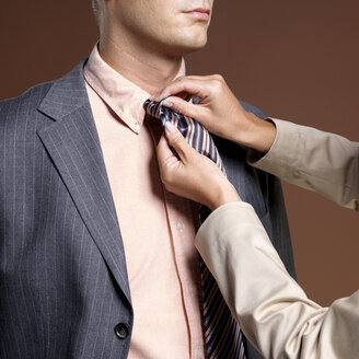 Woman binding businessman's tie - JLF00240