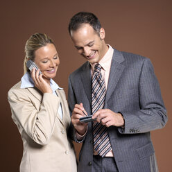 Geschäftsmann und Geschäftsfrau mit Mobiltelefon - JLF00238