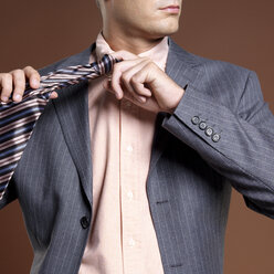 Businessman adjusting tie, mid section - JLF00230