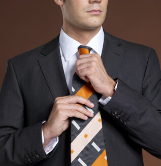 Businessman adjusting tie, mid section - JLF00215