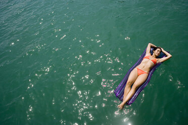 Young woman relaxing on air matress, floating in water - WWF00206