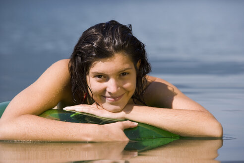 Junge Frau auf schwimmendem Reifen im See liegend - WWF00181
