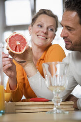 Älteres Paar isst Grapefruit in der Küche, Frau lächelt - WESTF03302