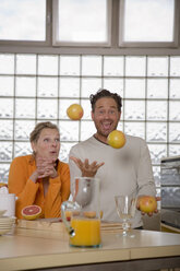Älteres Paar in der Küche, Mann jongliert mit Grapefruits - WESTF03297