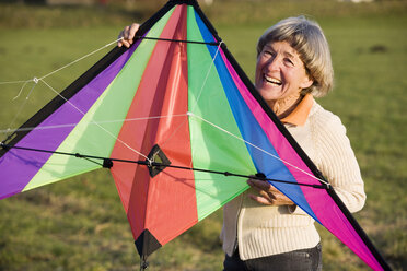 senior adult woman holding kite, smiling - WESTF03523