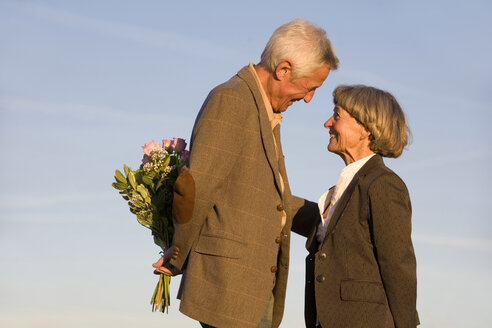Älteres Paar, Mann versteckt Blumenstrauß, lächelnd, Seitenansicht - WESTF03477