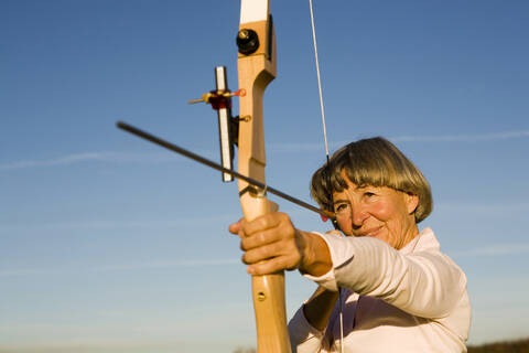 Ältere erwachsene Frau mit Pfeil und Bogen, lizenzfreies Stockfoto