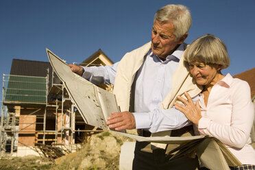 Älteres Ehepaar mit Plan vor einem teilweise gebauten Haus - WESTF03456