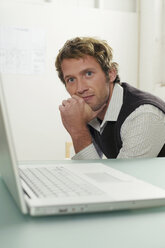 Young man sitting by laptop, portrait - WESTF03563