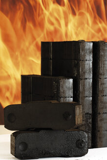 Piled briquettes, fire in background - 05478CS-U