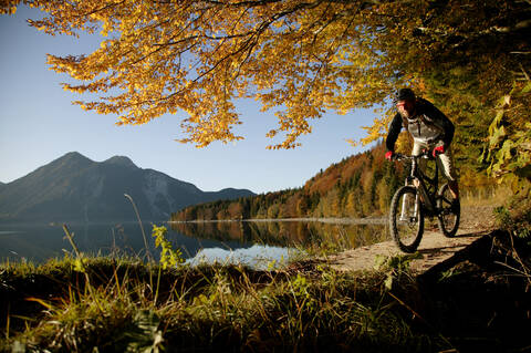 Junger Mann beim Mountainbiken im Wald, lizenzfreies Stockfoto