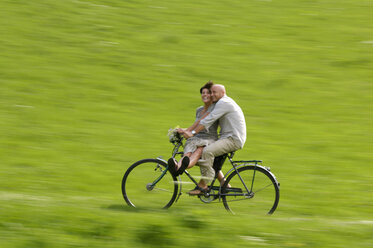 Couple riding bicycle in meadow - HHF00899