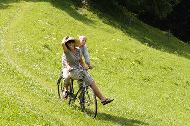 Couple riding bicycle in meadow - HHF00897