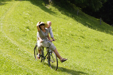 Paar fährt Fahrrad auf einer Wiese - HHF00897