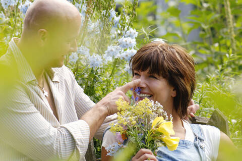 Ehepaar im Garten mit Frau, die einen Blumenstrauß hält, lizenzfreies Stockfoto