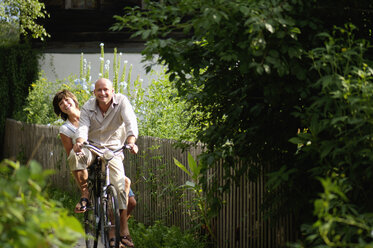 Couple riding bicycle, smiling - HHF00881