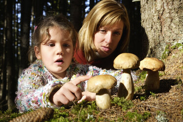 Mutter und Tochter beobachten Steinpilze im Wald - HHF00866