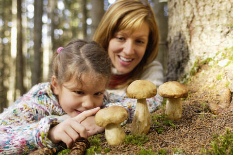 Mutter und Tochter beobachten Steinpilze im Wald, lizenzfreies Stockfoto