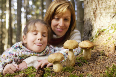 Mutter und Tochter beobachten Steinpilze im Wald - HHF00864