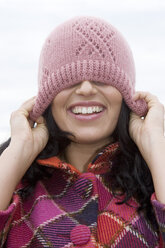 Young woman eyes covered by cap, smiling, close-up - LDF00382