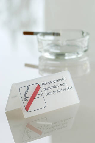 Zigarette im Aschenbecher neben dem Nichtraucherzeichen, lizenzfreies Stockfoto
