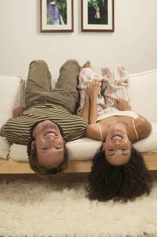 Junges Paar liegt kopfüber auf dem Sofa, lizenzfreies Stockfoto