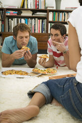 Drei junge Leute liegen auf dem Boden und essen Pizza - WESTF03702